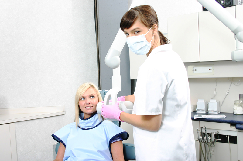 Hygienist taking dental X-rays of woman