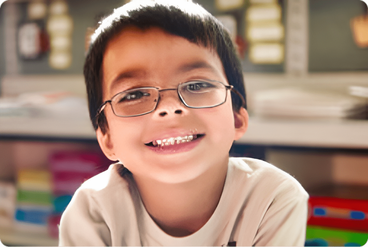 A young boy wearing glasses and smiling for the camera.