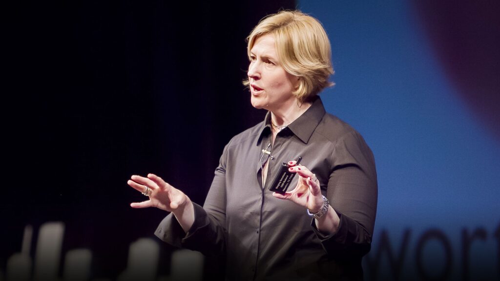 A woman is speaking on stage with her hands in the air.