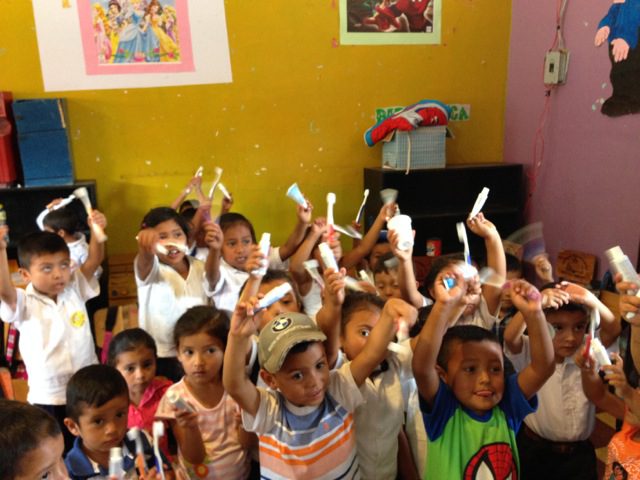 A group of children holding up white toothbrushes.