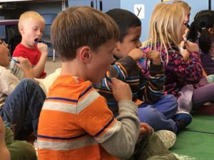 A group of children sitting on the floor eating food.