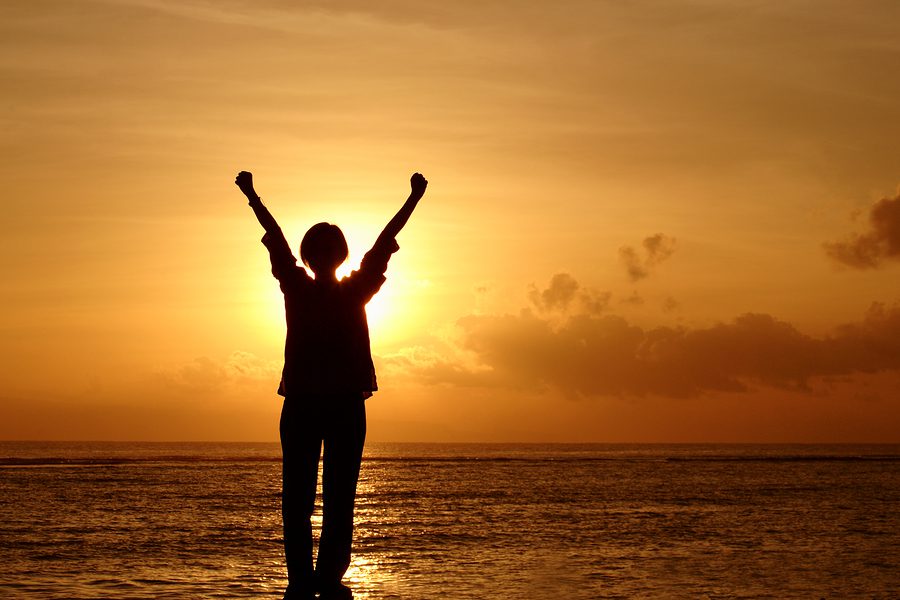 A person standing on the beach with their arms in the air.