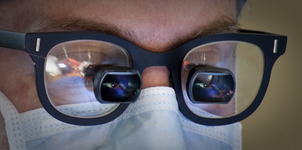 A person wearing glasses with their face reflected in them.